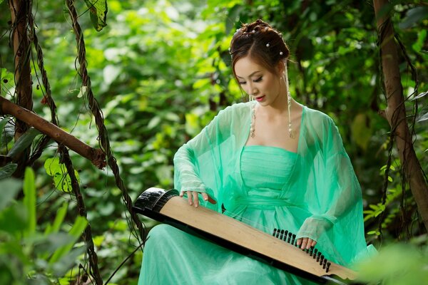 Asian girl plays a musical instrument in the forest