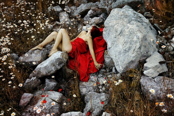 Photo professionnelle d une fille modèle en robe rouge. Dans une robe rouge sur un fond de pierres