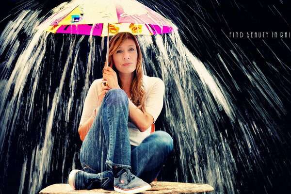 A girl hides under an umbrella from the flow of water