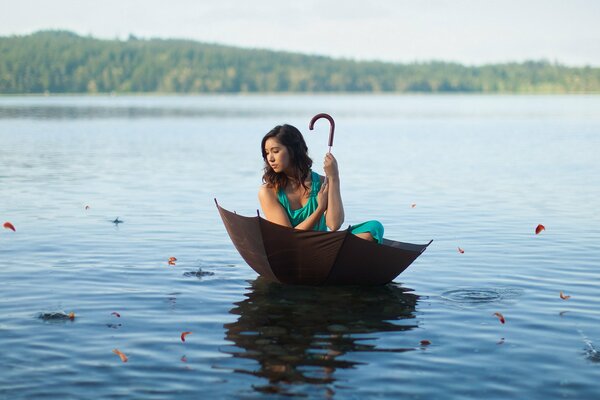 Fille nage sur le lac dans un parapluie