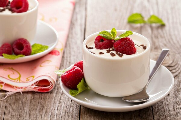 Weiße Tasse mit Sahne, garniert mit Himbeeren