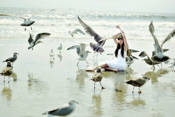 Fille au bord de la mer photographiée avec des oiseaux