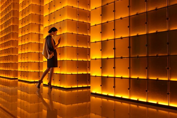 The girl stands against the background of a wall of small squares