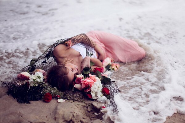 The girl lies in the sea foam with flowers