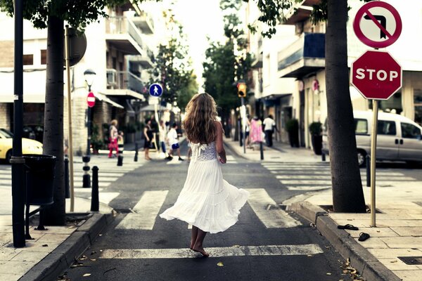 A girl in a white dress walks around the city