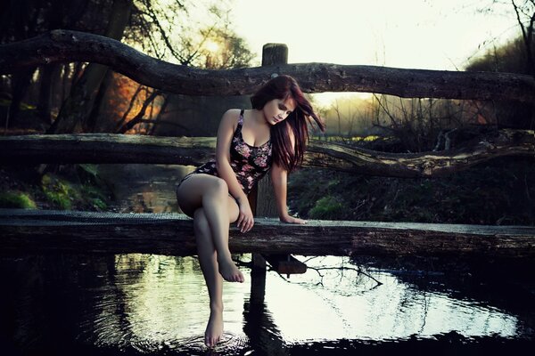 A girl in a swimsuit is sitting on the bridge