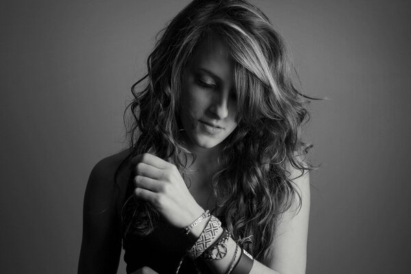 Black and white photo. Beautiful girl with wavy hair and bracelets on her arm