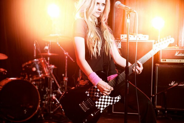 Avril Lavigne con guitarra en el escenario