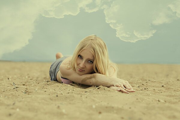 Blonde on the sand under the clouds