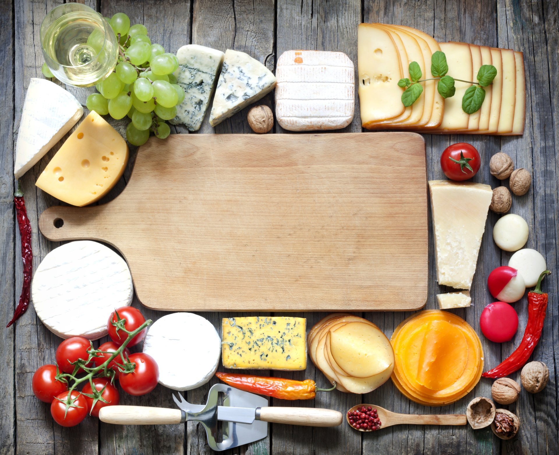 board cheese walnuts glass wine white grapes pepper tomatoes spatula