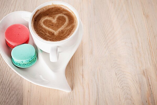 A cup of coffee with a heart on foam and two cakes