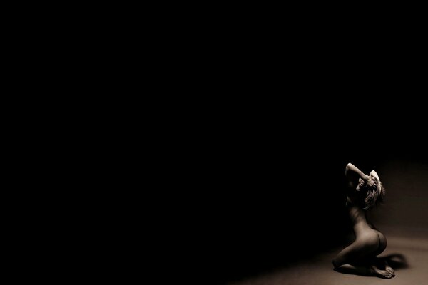 Naked girl holding her head on a dark background