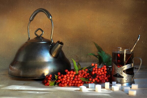 A teapot and a cup of tea on the table. Red berries with tea