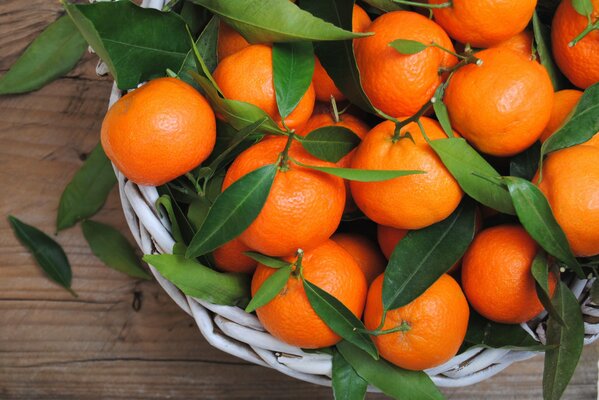 Collected oranges with leaves on a plate on the table