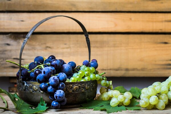 Racimos de uvas blancas y rojas en la mesa y en la cesta