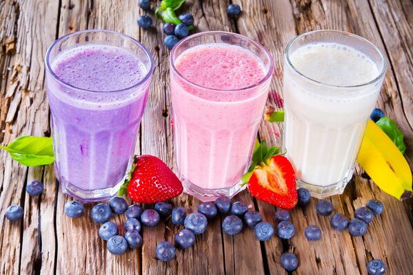 Three glasses with a milkshake and berries on the table