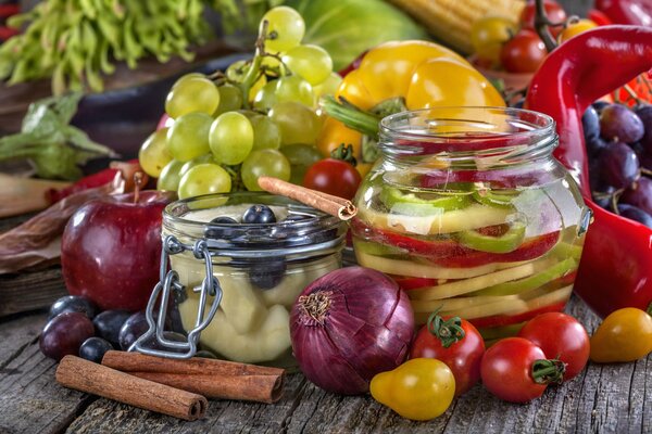 En la mesa hay espacios en blanco enlatados, frutas, verduras y bayas