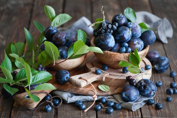 Still life of plums and blueberries on wooden dishes