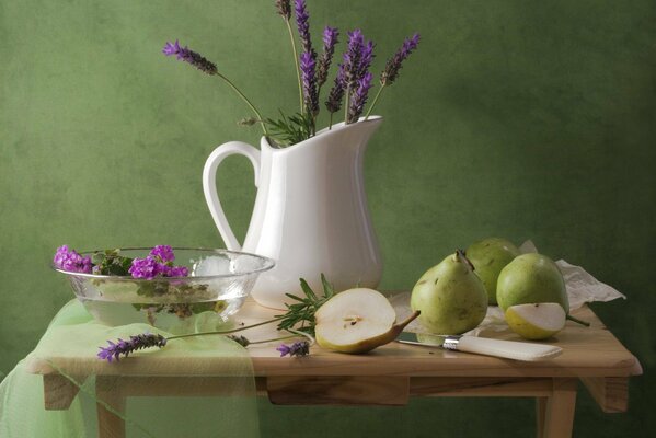 Ein Krug mit Lavendel auf einem Holztisch mit Birnen