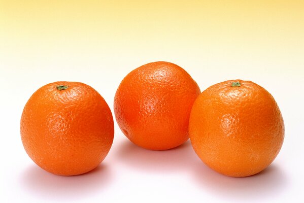 Three bright oranges on a white background