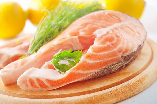 Red salmon steak on a wooden board decorated with greens