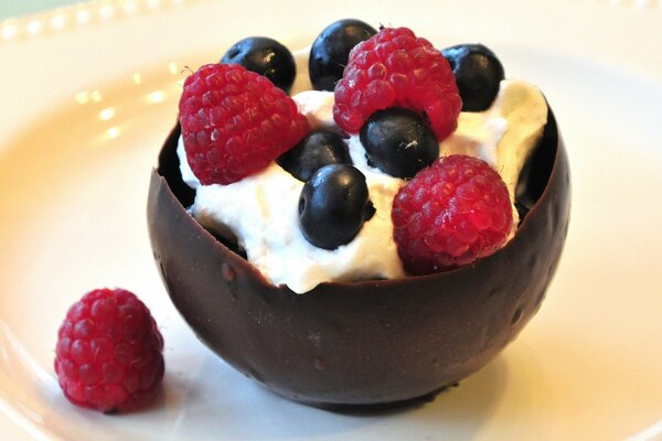 Dessert in a chocolate bowl with cream raspberries and blueberries