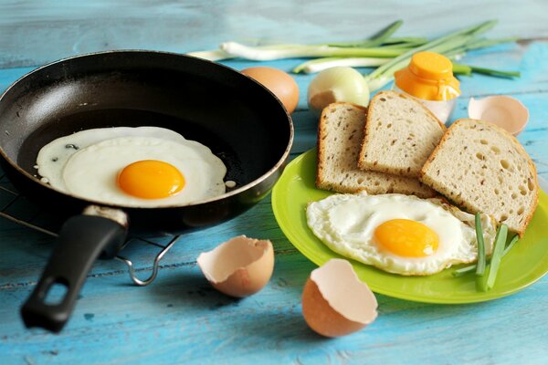 Still life of fried eggs in a frying pan, bread and onions