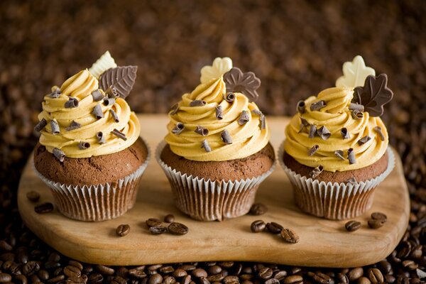 Tres cupcakes en una tabla con crema y chocolate