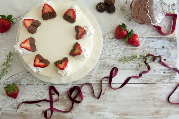 Still life with the image of a strawberry cake and a decorative ribbon on the table