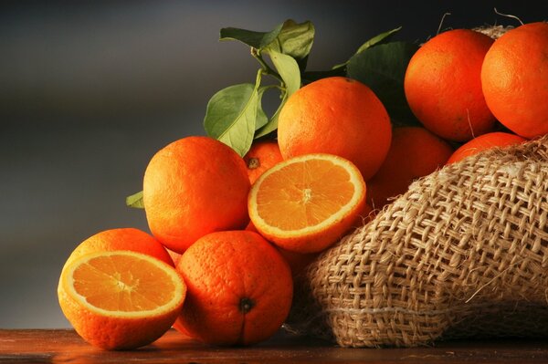 Whole and sliced oranges on a bag