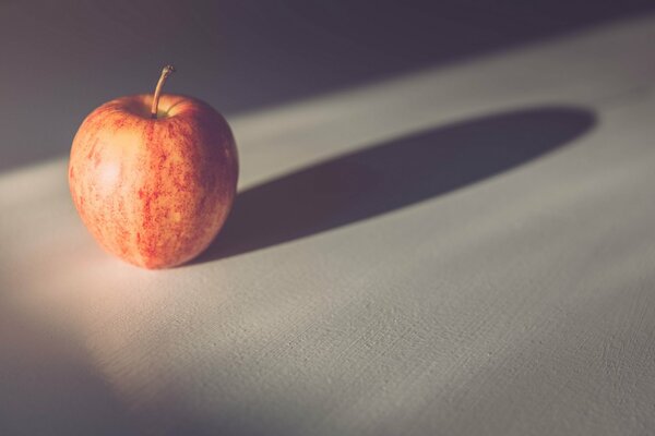 A lonely red apple on a white tablecloth