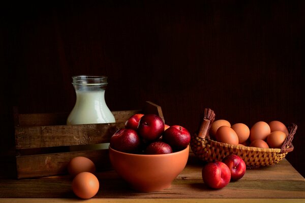 Red apples and milk with eggs on a black background