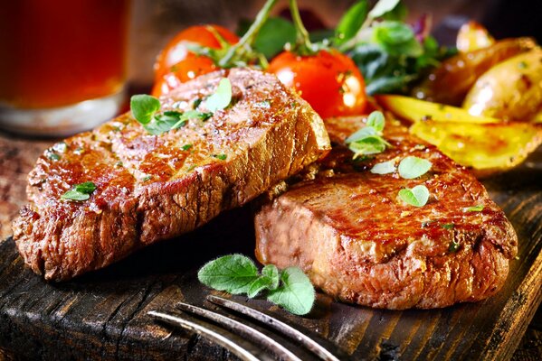 Morceaux de viande juteuse avec des légumes sur le tableau noir