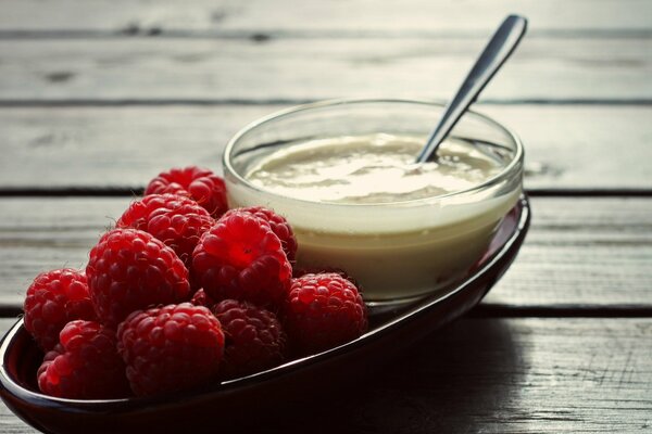 Photo of berries on a wooden background. Raspberry wallpaper on a plate