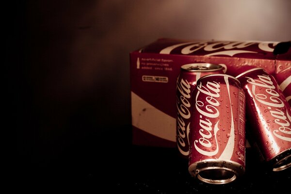 Tres latas de Coca cola al lado de la Caja