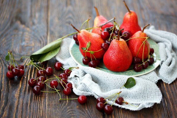 Naturaleza muerta de cerezas y peras sobre un fondo de madera