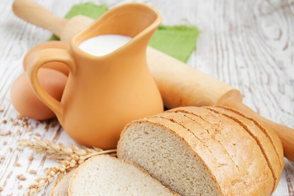 Eggs jug milk bread and rolling pin on the table