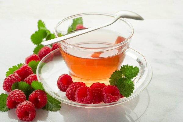 A cup of tea and raspberries on the table