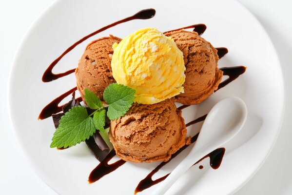 Dessert aus Schokolade und Mango-Eis mit Minze auf einem Teller