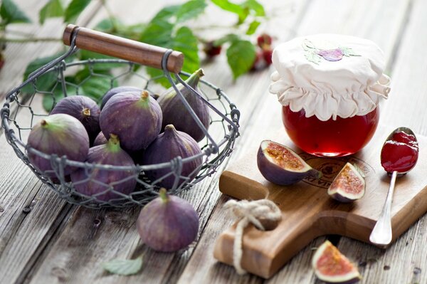 Figues dans un panier à côté d un pot de confiture sur une planche de bois