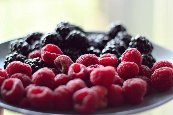 Fond d écran avec des framboises fraîches et des mûres sur une assiette