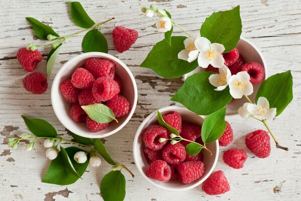 Tazze con bacche di lampone e fiori di gelsomino