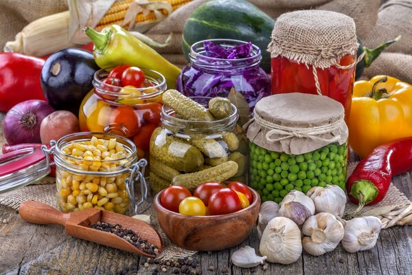 Concombres en conserve, oignons, ail et pois dans un pot sur une table en bois