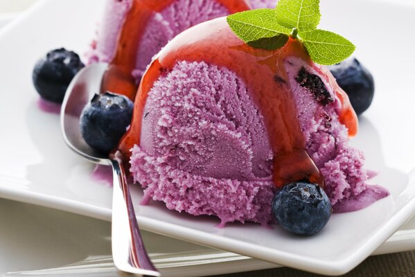 Helado vertido en jarabe con hojas de menta y arándanos