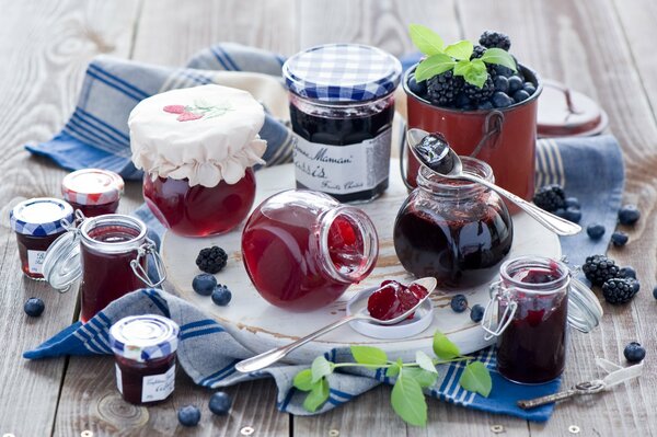 Pots de confiture à côté des bleuets et des mûres