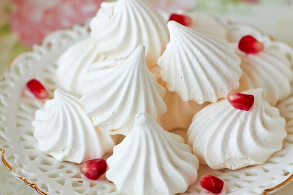 Merengue blanco en un plato con granos de Granada