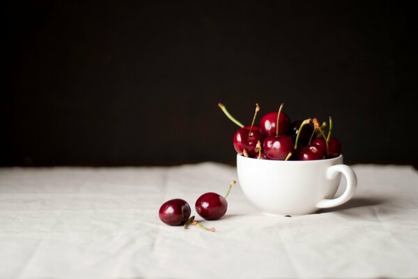 Cerise sur la table dans une tasse blanche