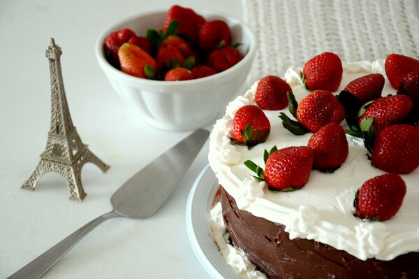 Torta al cioccolato con fragole sul tavolo con la statuetta della Torre Eiffel accanto