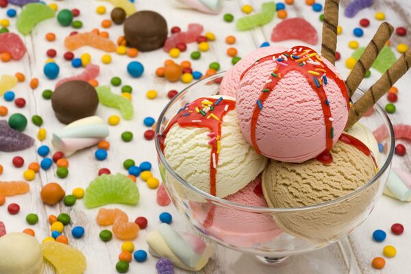 Dessert ice cream in a glass on a background of colorful candies