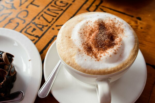 Cappuccino mit Schaum und Kuchen auf einem Teller